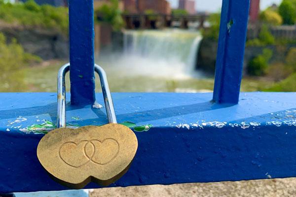 A lock with two hearts on the railing of the bridge.