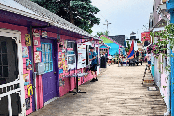 Shops in bright pink line a boardwalk near the Olcott Beach Carousel Park