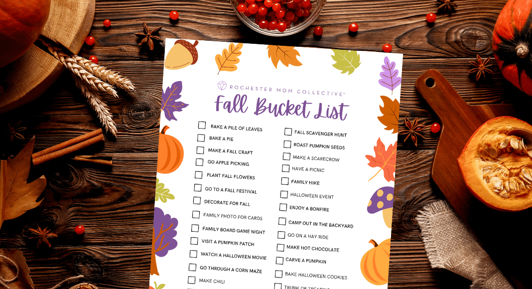 A fall bucket list printable sits on a table with pumpkins, berries and cinnamon sticks.