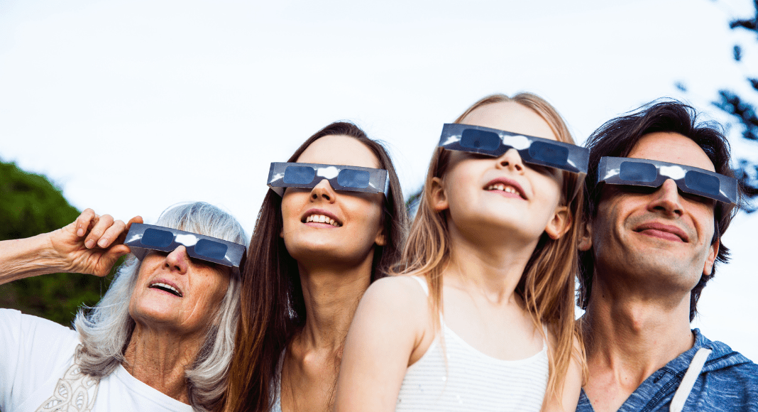 A family wears solar glasses looking at an eclipse in Solar Eclipses In Rochester