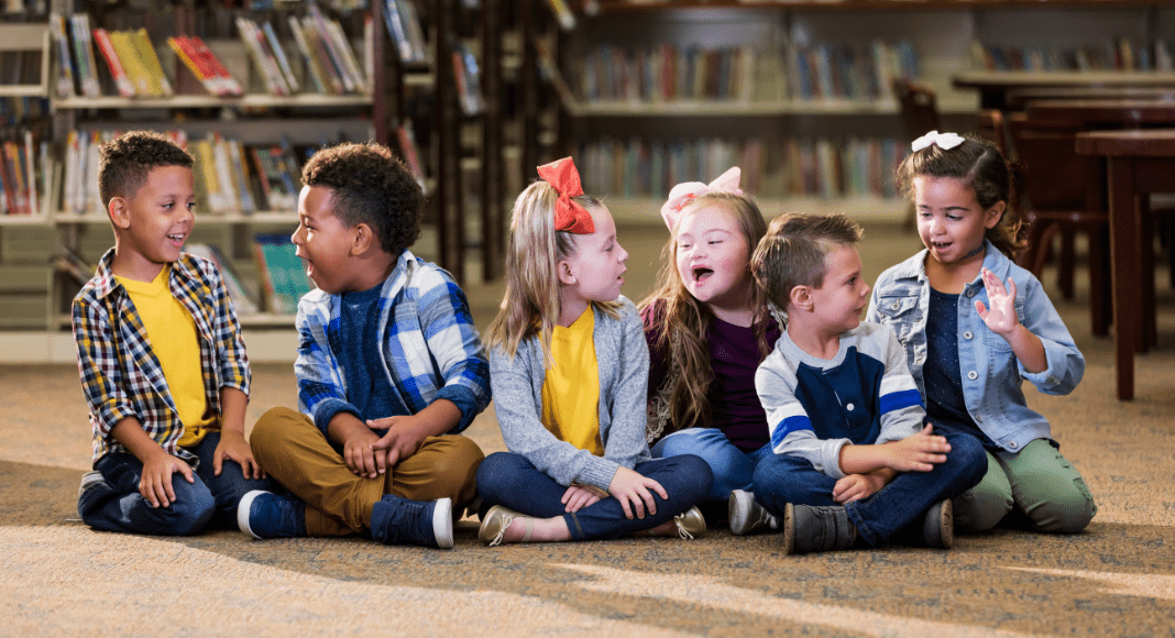 Children sit together on the floor of the library