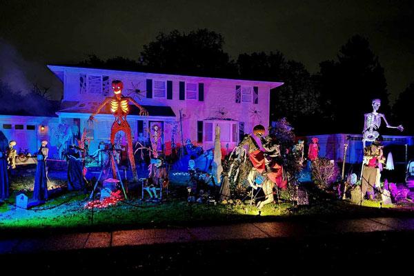 Skeletons and creatures are gathered on the front lawn of a house.