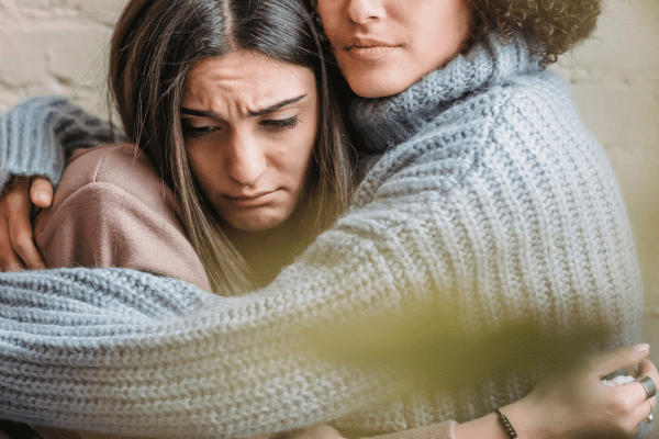 A woman hugs a grieving friend.
