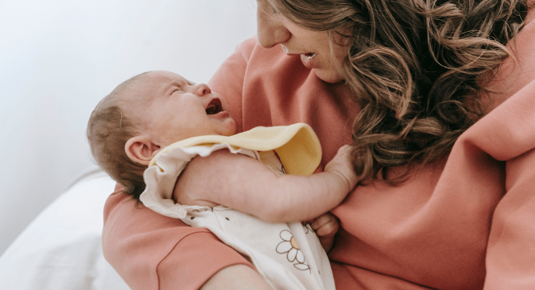 A mom holds a crying baby.