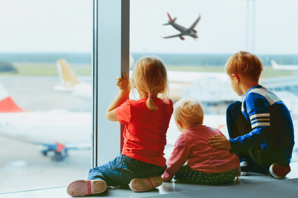 Kids watch airplanes at an airport.