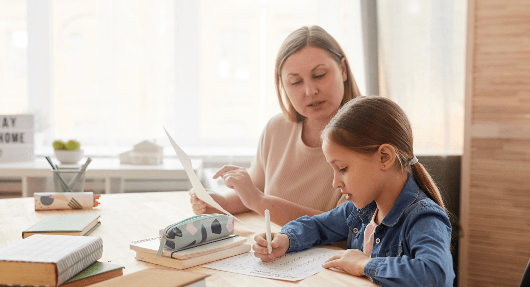 A mom sits with her daughter doing math homework.