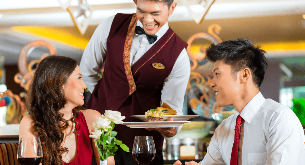 A waiter brings a couple their meal at a restaurant.
