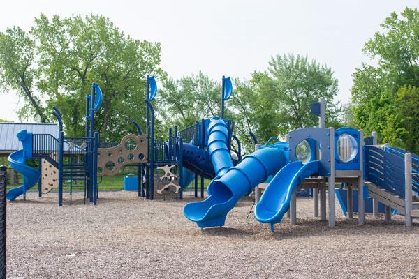 A small and a large playground structure in bright blue with slides and sail flags.