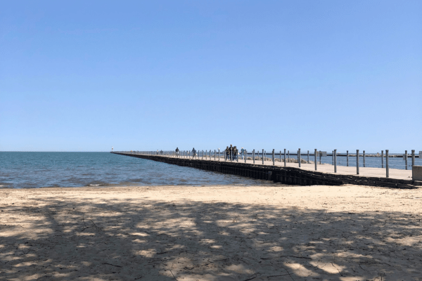 A sandy beach and pier that stretches into Lake Ontario.