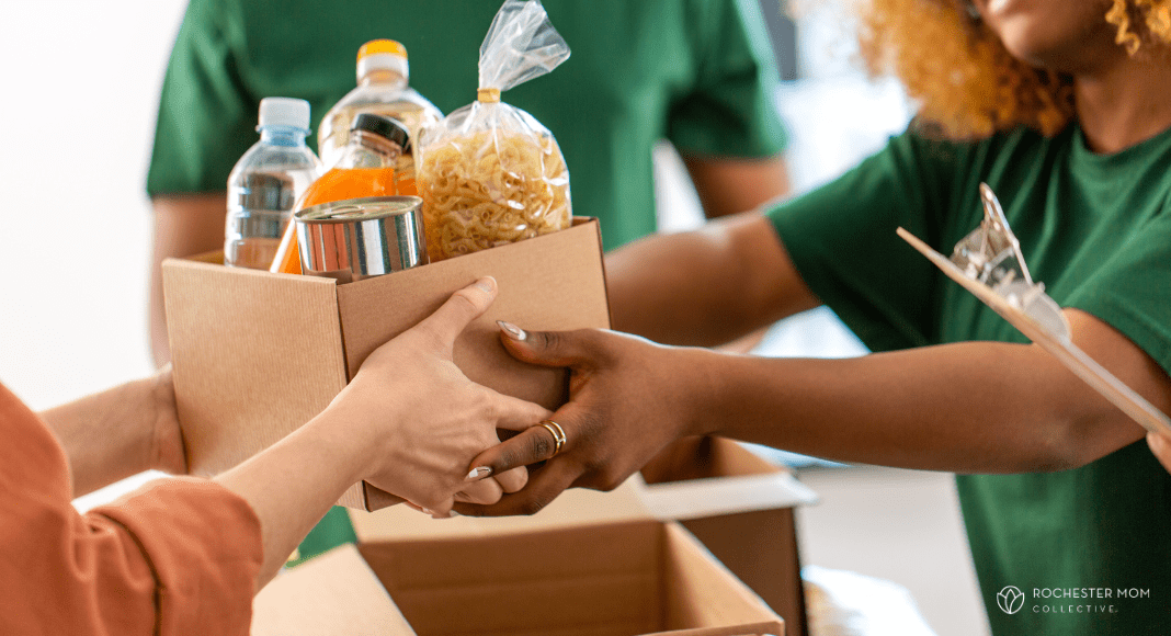A volunteer hands a box with food items to someone.