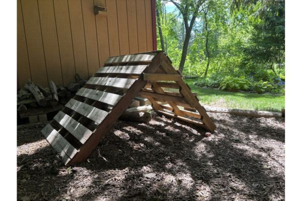 Children's triangle step climber made from wood in an outdoor setting.